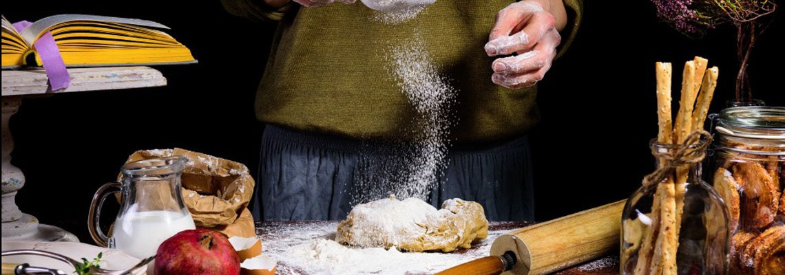 Bild mit Frau am Tisch und vielen Gewürzen und Zutaten