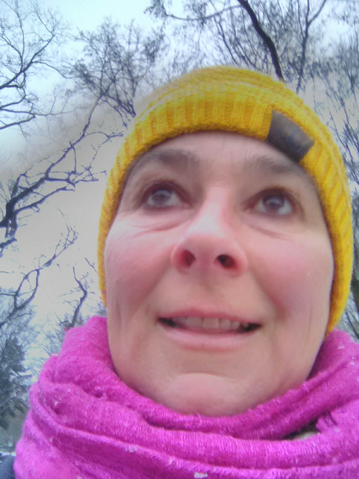 Ein Foto von einer Frau mit rosa Schal und einer gelben Mütze auf dem Kopf. 