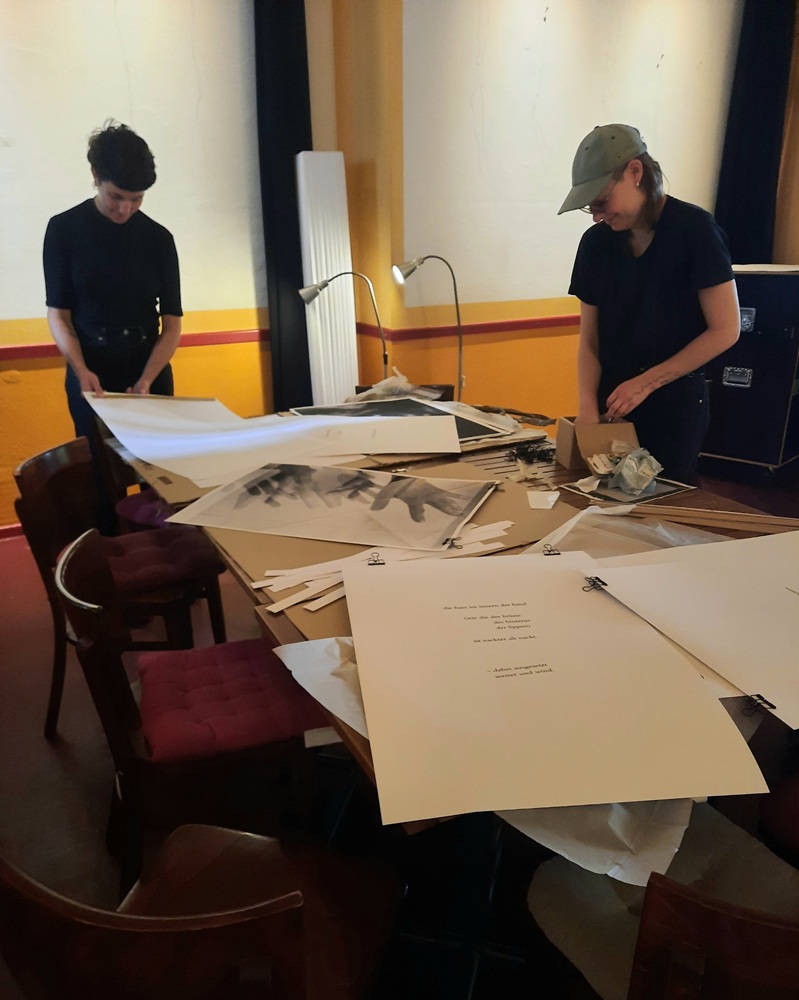 Zwei junge Frauen bauen eine Ausstellung auf. 