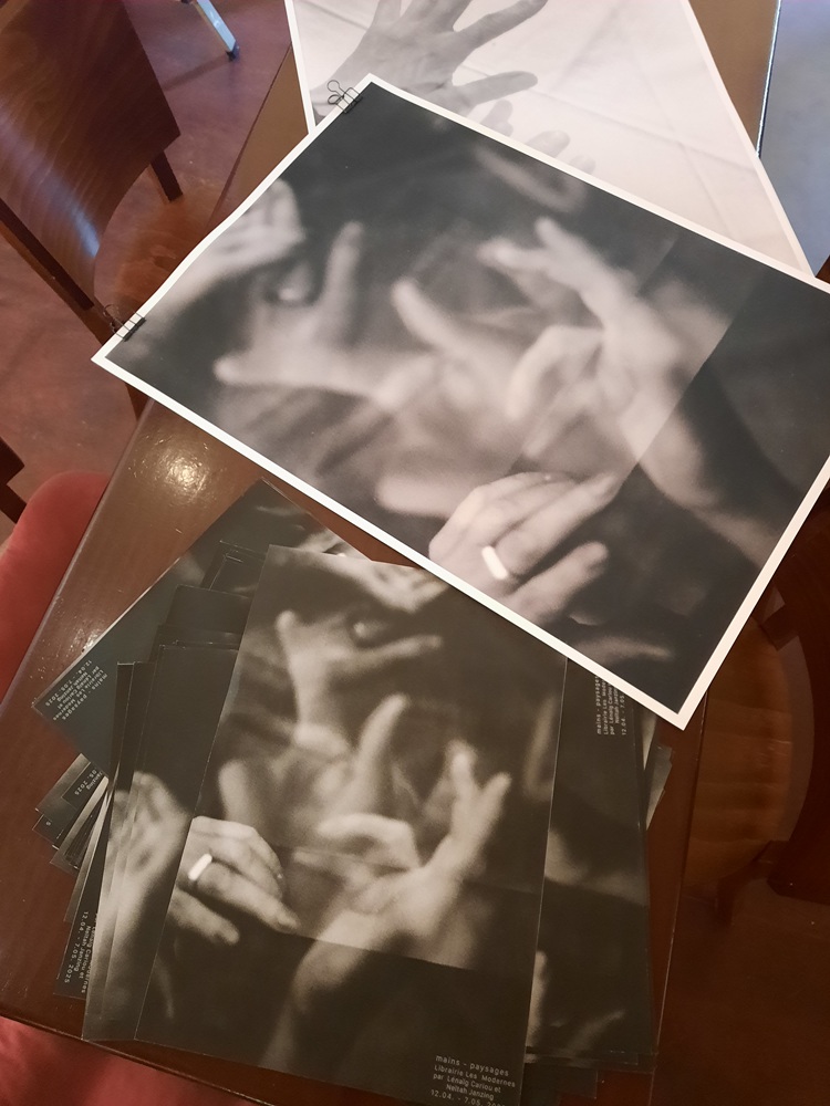 Viele schwarzweiße Poster liegen aufeinander auf einem Tisch. 