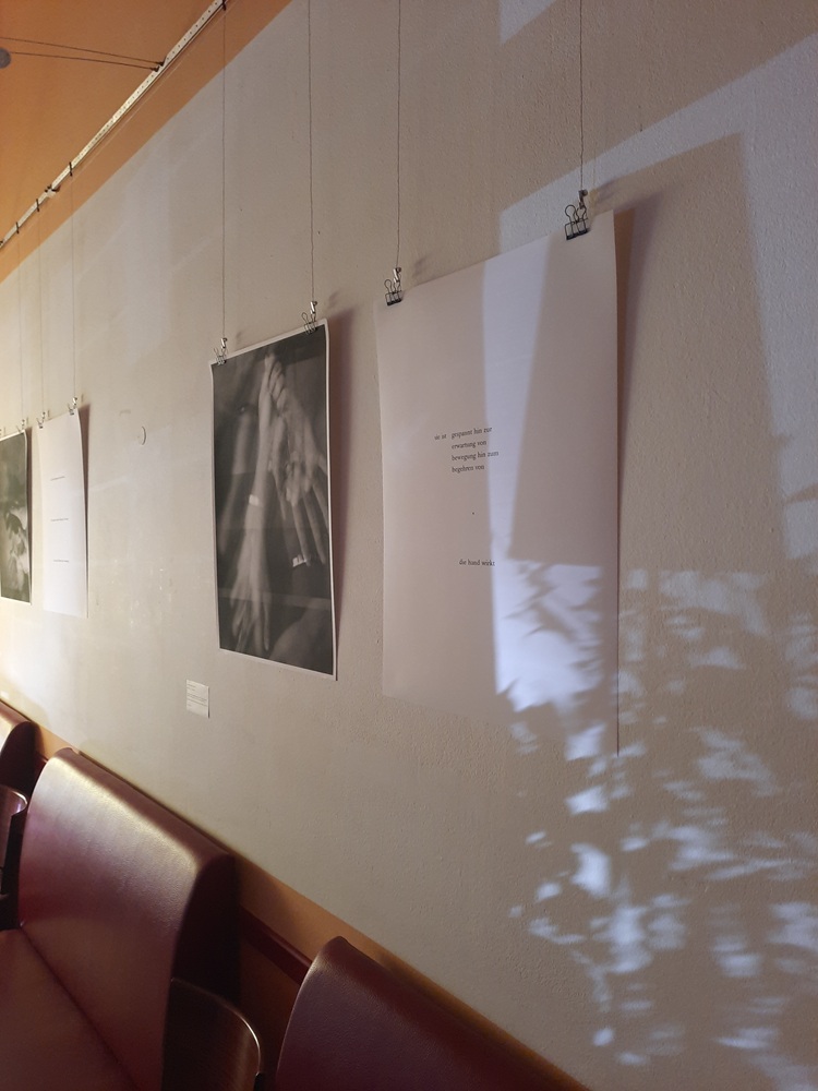 Ein schwarzweißes Foto und ein großes Papierblatt hängen an einer Wand