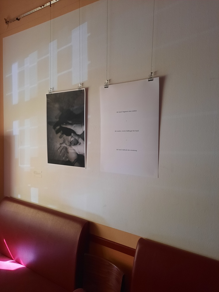 Ein schwarzweißes Foto und ein großes Papierblatt hängen an einer Wand