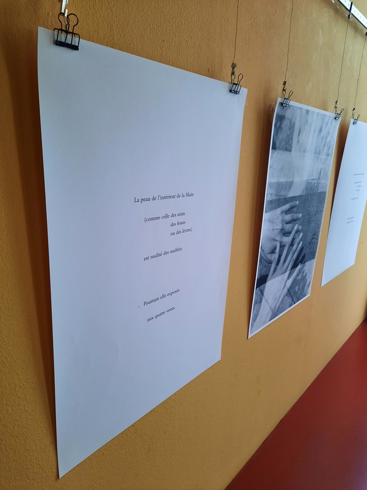 Ein schwarzweißes Foto und ein großes Papierblatt hängen an einer Wand