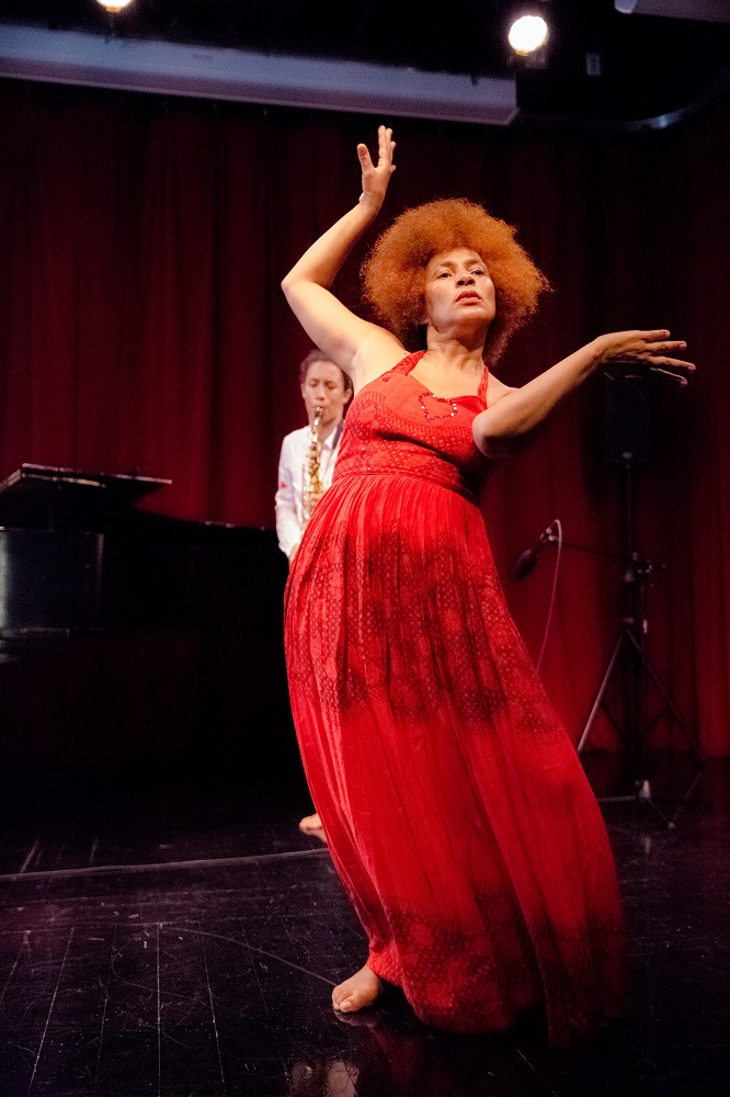 Ein Foto von einer Schwarzen tanzenden Frau mit rotem Kleid. 