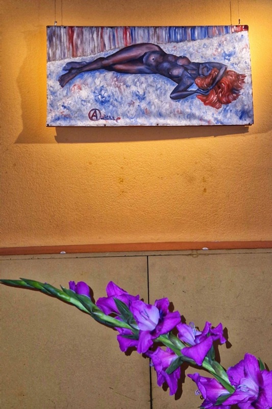 Ein Foto von einem Ölbild mit einer liegenden nacjken Frau. Unten eine Blume.