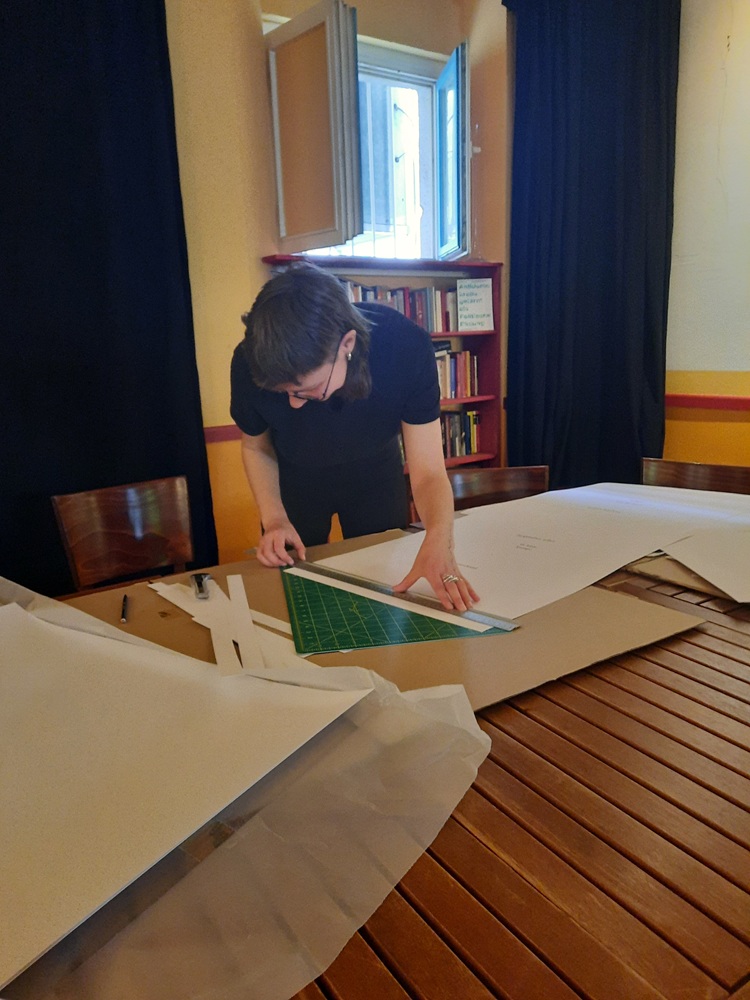 Eine junge Frau arbeitet am Tisch mit Papier und Lineal
