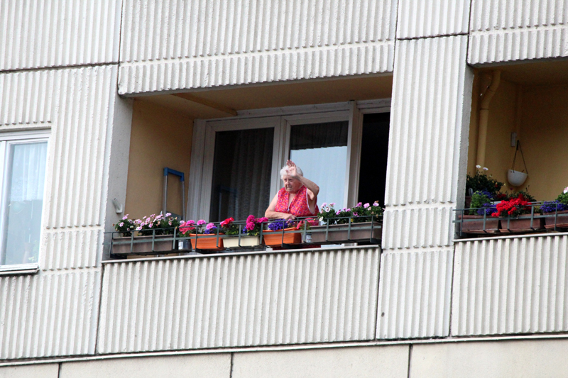 Bild einer winkenden Frau vom Balkon